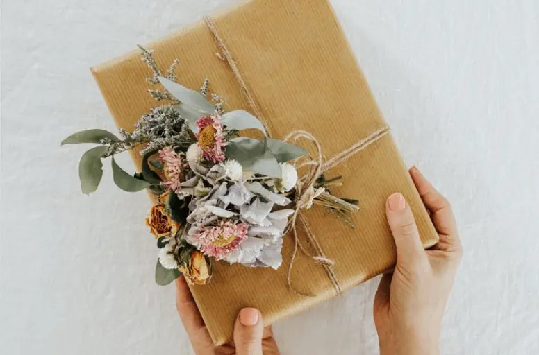 Adding dried flowers for decorative accents in Etsy packaging 